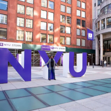 Man Standing Infront Of The NYU Letter Boards